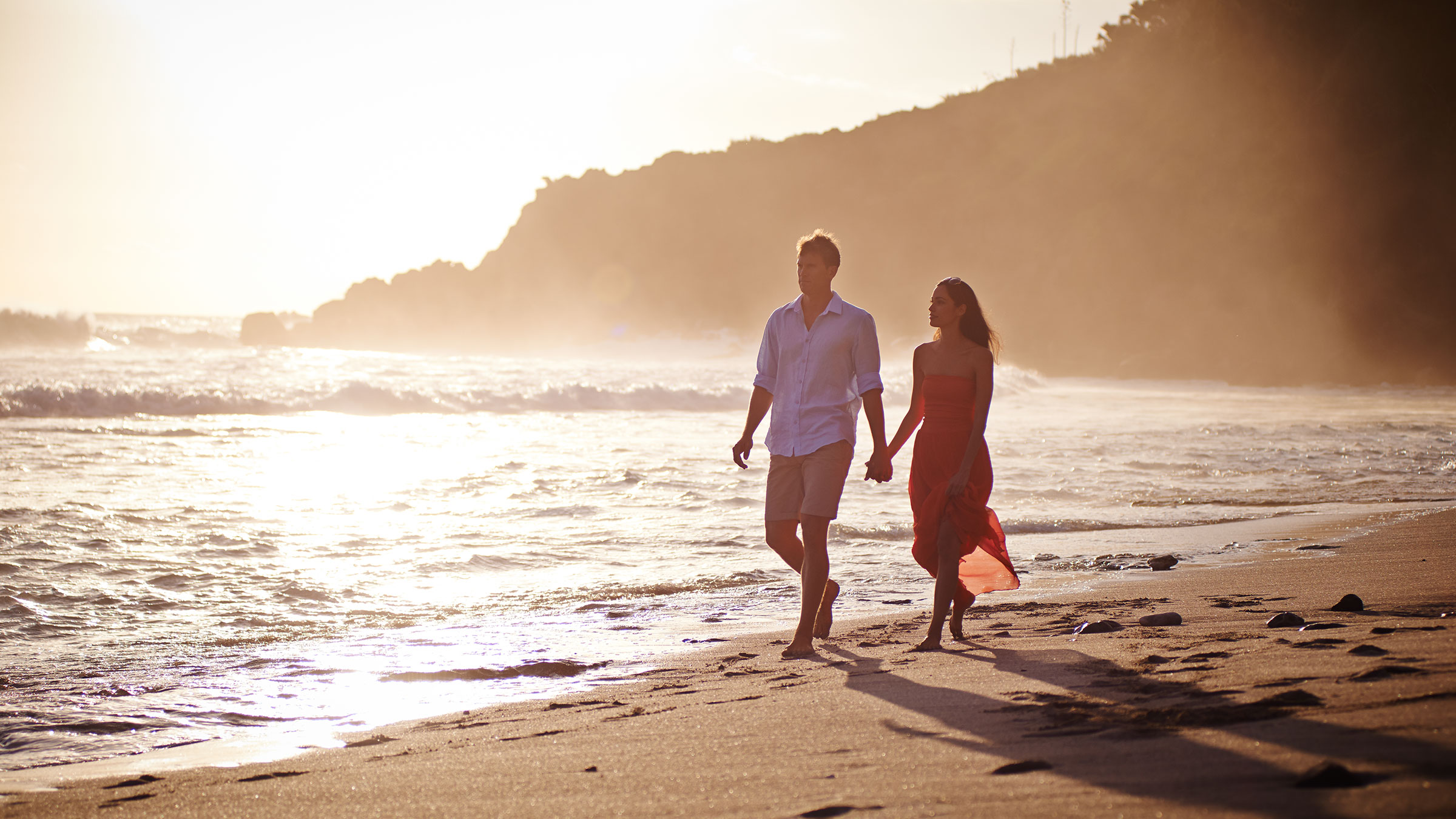 Un couple marche main dans la main sur la plage de Grande Anse